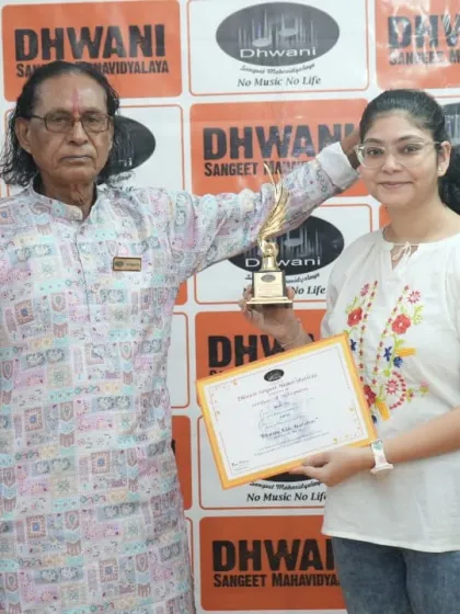 A senior guru presents an award to an adult student, honoring her commitment.