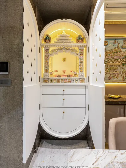 The mandir doors open to reveal a beautifully lit, traditional marble temple. This design is perfect for modern apartments where space is a premium, offering a divine sanctuary that can be neatly tucked away.