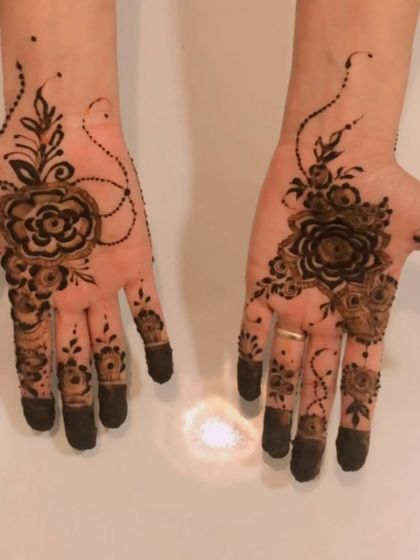 A classic Arabic rose design on the palms. The central flower motif is surrounded by delicate vines and dots, creating a simple yet beautiful look with filled fingertips.