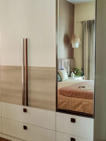 This bedroom showcases how to store in style. The floor-to-ceiling wardrobe features a mix of fluted and wood-grain finishes with rose gold handles, while the integrated mirror adds functionality and reflects light beautifully.