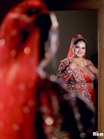 A creative shot of the bride looking at her reflection in a mirror, with the reflection in focus, creating an artistic and introspective portrait.