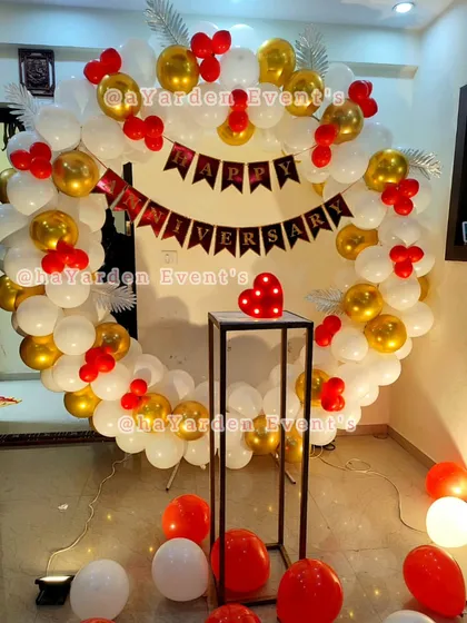 A beautiful 'Happy Anniversary' balloon ring in red, white, and gold. This is a classic and romantic choice for celebrating your special day at home.