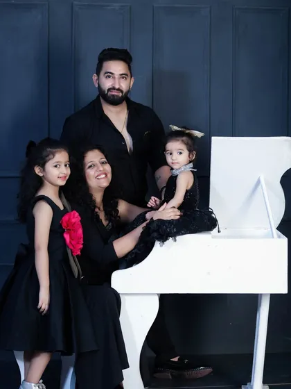 A chic and elegant family portrait using our white piano prop. The coordinated black outfits create a striking contrast, resulting in a sophisticated and modern family photo.