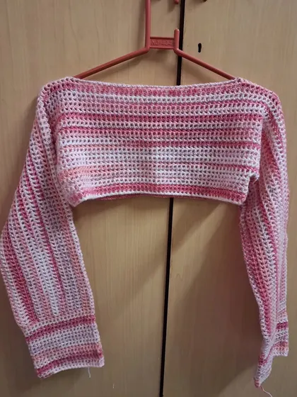 The pink mesh bolero hanging, showing its shape and drape.
