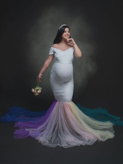 Draped in lace and crowned with grace, this mama-to-be embodies strength and serenity in a white gown with a rainbow tulle train.