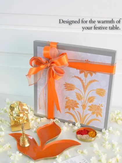 Designed for the warmth of your festive table. This image captures a complete gift set, featuring our orange Pushpa tray alongside a Ganesha idol and a beautifully wrapped box, embodying the spirit of celebration.
