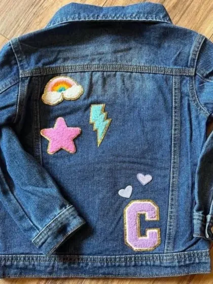 This denim jacket is personalized with the initial "C" and fun patches like a rainbow, star, and lightning bolt.