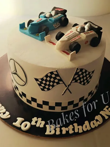 A Formula 1-themed cake with two handcrafted, edible race cars on top. The checkered flag design around the base completes the high-speed look.