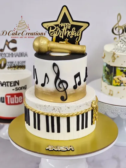 A two-tier music-themed cake with a golden microphone, piano keys, and musical notes, created for musician Anish Chhabra.