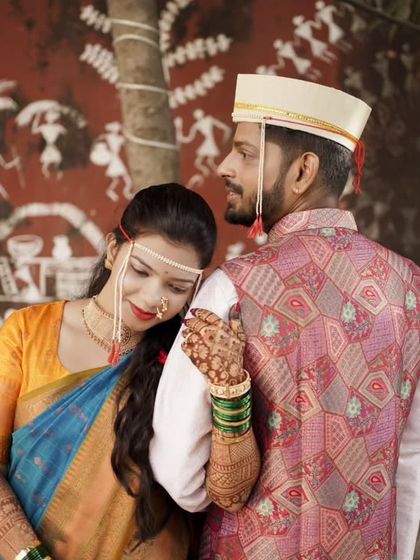A tender moment with the bride resting her head on the groom's shoulder, set against a backdrop of traditional art.