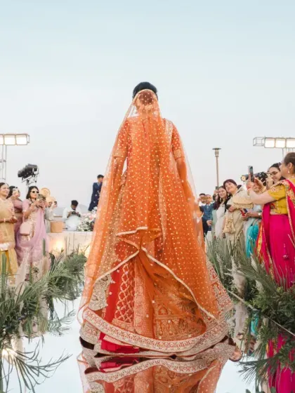 The bride's grand entrance down a mirrored aisle, her long veil trailing behind her. The guests' loving expressions and the stunning reflection create a powerful and emotional frame.