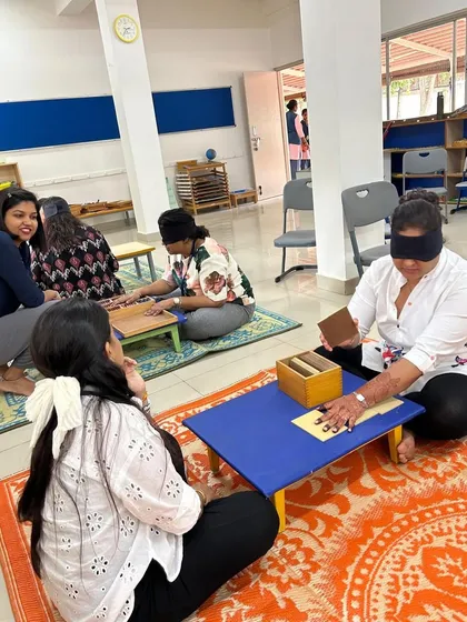 Teachers at Legacy School engage with the baric tablets, a sensorial material used to refine the sense of weight. Experiencing this helps them guide children more effectively.