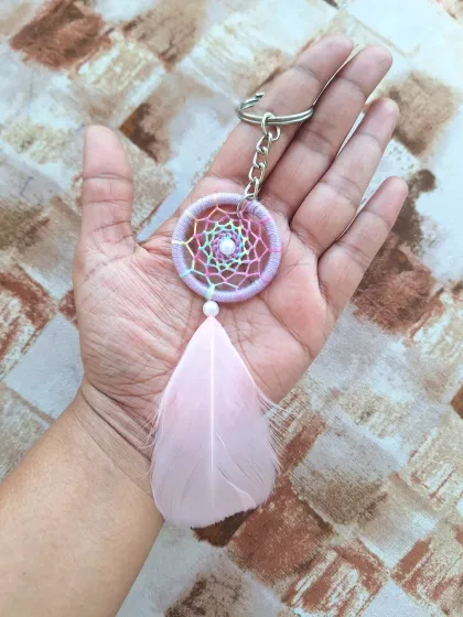 A dreamy, pastel rainbow dreamcatcher charm with a soft pink feather, perfect for those who love subtle color.