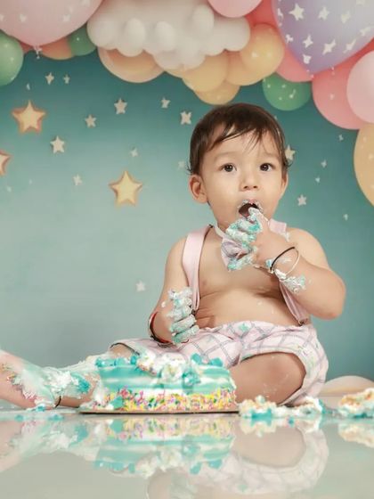 It's not a party until the cake is everywhere! This little one is thoroughly enjoying his first taste of birthday cake during his fun cake smash session.