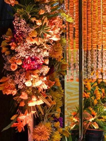 Another detail of the floral arch, highlighting the different textures and shades within the arrangement. The hanging marigold curtain adds a traditional element.