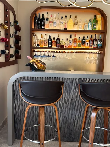 A close-up of the custom bar, highlighting the textured front panel, sleek countertop, and modern bar stools.