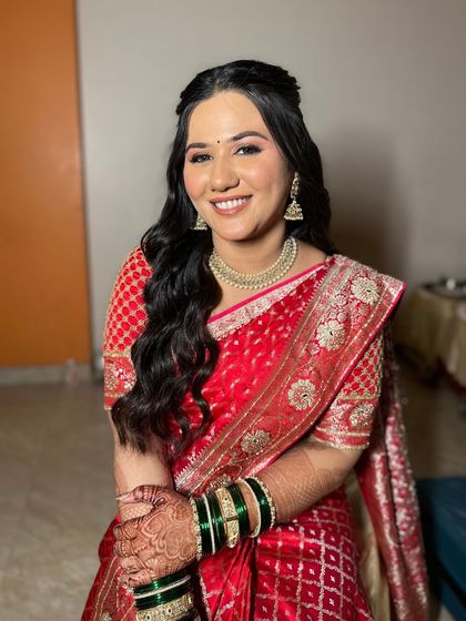 The final engagement look, glowing and happy. Her red bandhani saree is beautifully complemented by a natural makeup look with soft waves in her hair, making her shine.