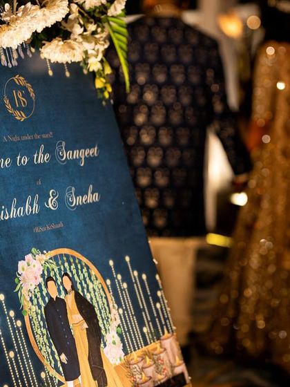 A beautifully designed welcome sign for Rishabh and Sneha's Sangeet. The deep blue background, sparkling lights, and custom couple illustration create a warm and inviting entrance for a night of music and celebration.