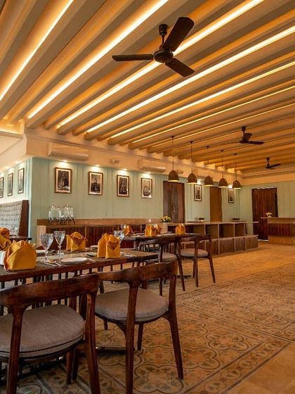 The interior of Ebony Restaurant in Whitefield, designed with a colonial-inspired theme. The ribbed ceiling with concealed lighting, classic furniture, and warm color palette create an inviting and timeless dining room.