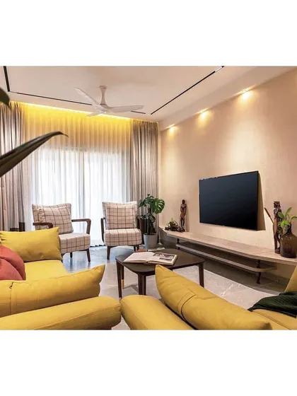 A view across the living room, showing the balance of the bold yellow sofa with the more subdued, classic armchairs. The space is designed for conversation and connection.