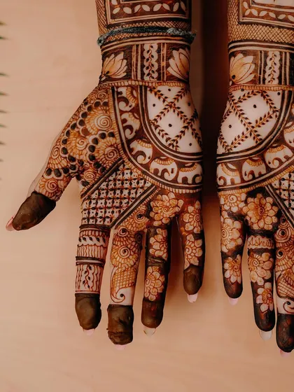 A close-up of a beautiful bridal design, focusing on the intricate floral and elephant patterns on the palm and fingers.