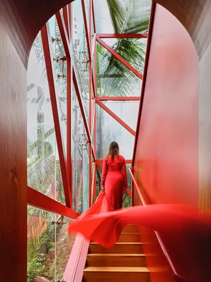 Architecture is art. In this Bangalore residence by Bodhi Design Studio, a crimson-red staircase becomes a dramatic, flowing sculpture, encased in glass to create a sense of levitation and movement against the lush green backdrop.