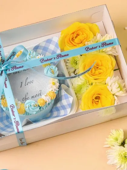 A beautifully packaged bakery hamper with a custom cookie and fresh flowers, tied with a branded ribbon.