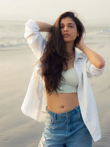 A confident and relaxed portrait. The combination of the open shirt and crop top is a classic beach-style look.