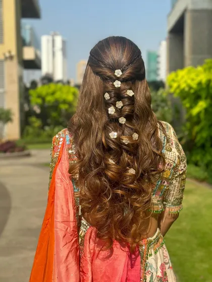 A full back view of the half-up style with dispersed flowers, a perfect hairstyle for an outdoor daytime wedding event.