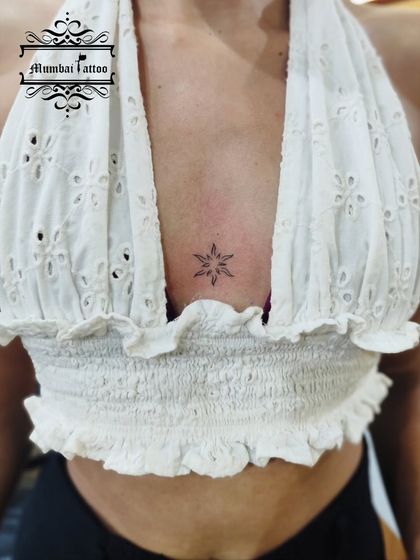 A minimal starburst or sun tattoo placed in the center of the chest. This is a simple yet radiant design, perfect for someone who wants to carry a little bit of light with them.