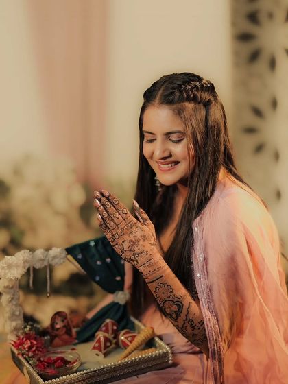 A candid photo of a bride during her mehandi ceremony, her smile showing her happiness with the intricate design on her hands.