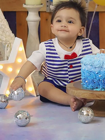 This little sailor is all set for his blue-themed cake smash! The nautical-inspired outfit and beautiful blue ombre cake make this first birthday session so special.