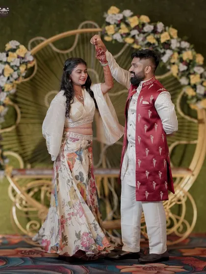 A joyful moment from a Sangeet or reception, where the groom twirls the bride under the lights of the decorated stage. This candid shot captures the fun and movement of wedding celebrations.