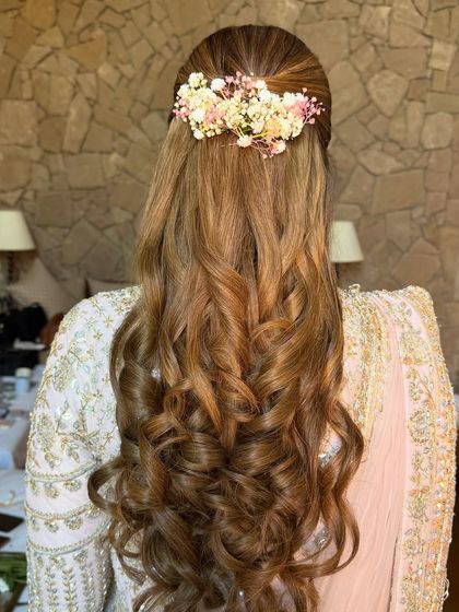 A soft glam half-up style with a beautiful barrette of fresh baby's breath and pink flowers, paired with voluminous curls.