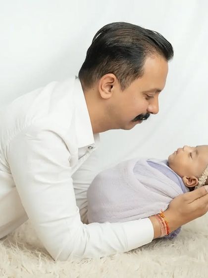 A father's gentle love for his newborn daughter, captured in a simple and clean studio setting.