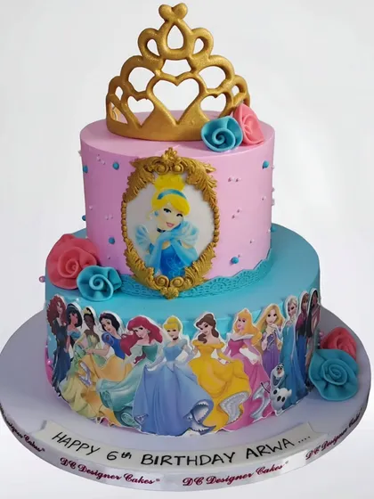 A two-tier Disney princess cake featuring Cinderella and an array of other beloved princesses. This whipped cream cake is decorated with a golden tiara and edible images for a magical 6th birthday.