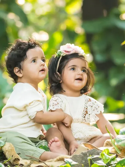 Twin toddlers exploring the textures and sights of a park. Outdoor sessions are perfect for capturing the natural curiosity of children.