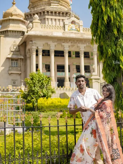 A beautiful shot of a couple in front of a government building, framed by greenery. We can turn any location into a romantic backdrop.