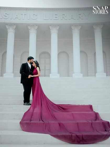 A timeless couple portrait on the steps of a classic colonial-style building. The long train of the gown cascading down the stairs creates a stunning visual for this pre-wedding photo.