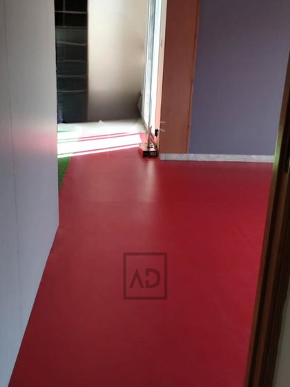 A view of the red sports flooring as it's being installed in a room. This seamless surface is easy to clean and maintains its color and performance over time.