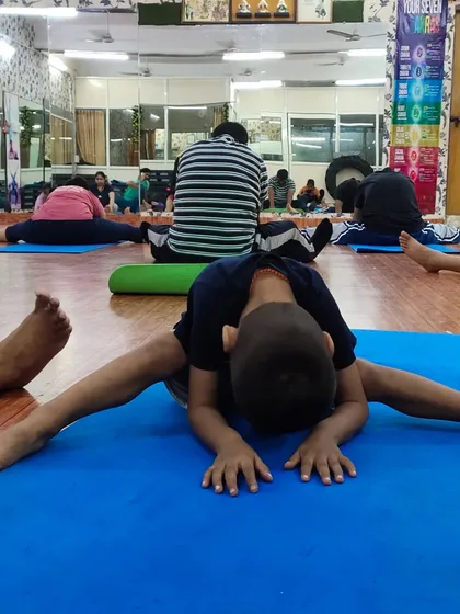 A close-up of the young student's deep forward split, showcasing his dedication and the results of regular practice. Flexibility is a key benefit of starting yoga early.