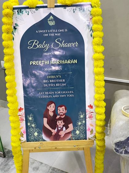 I provide custom welcome boards for all events. This easel sign for a baby shower features a personalized family illustration and event details, framed with marigold flowers.