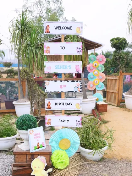 A rustic wooden signpost welcoming guests to "Seher's 4th Birthday Party." This, along with other themed props, created a charming and personalized entrance.