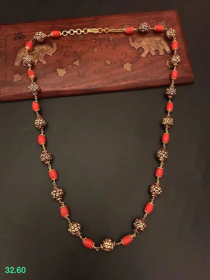 Another view of the red beaded necklace with ornate golden beads. The quality of the materials and craftsmanship is evident in this beautiful piece.