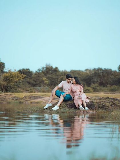 A wide, scenic shot of a couple enjoying a peaceful moment by the water's edge, with their reflection creating a beautiful symmetry. This highlights my love for epic, scenic couple photography.