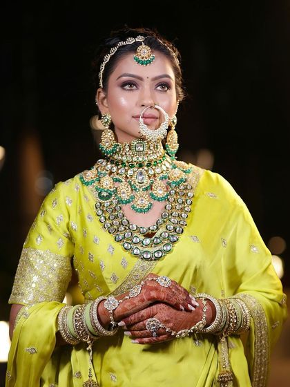 A bride glowing in a unique lime-yellow lehenga. The heavy green jewelry and flawless makeup make this a standout look.