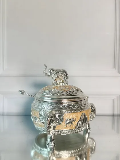 Here is the elephant-topped box in a warm, creamy beige enamel. This neutral tone allows the intricate silver engravings of the elephant and landscape to truly shine.