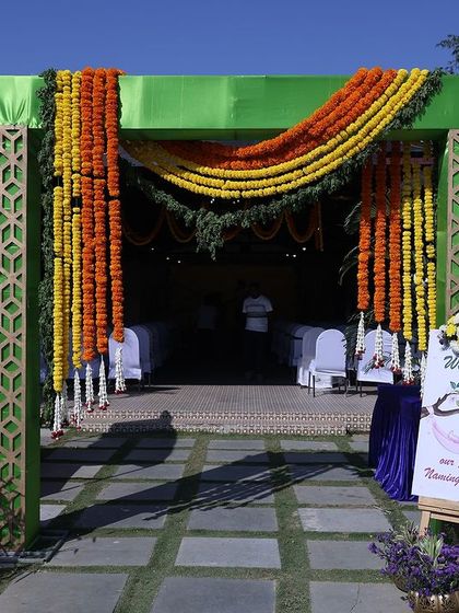 A welcoming entrance arch for a naming ceremony, decorated with bright orange and yellow marigold garlands.