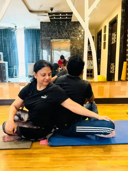 A seated spinal twist with a partner during a home session. This pose helps to detoxify the body and improve spinal mobility, and the partner connection adds gentle resistance for a deeper twist.