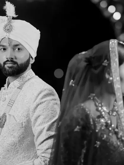 A powerful black and white portrait of the bride and groom. The back-to-back pose is classic and cinematic, creating a sense of partnership and strength.